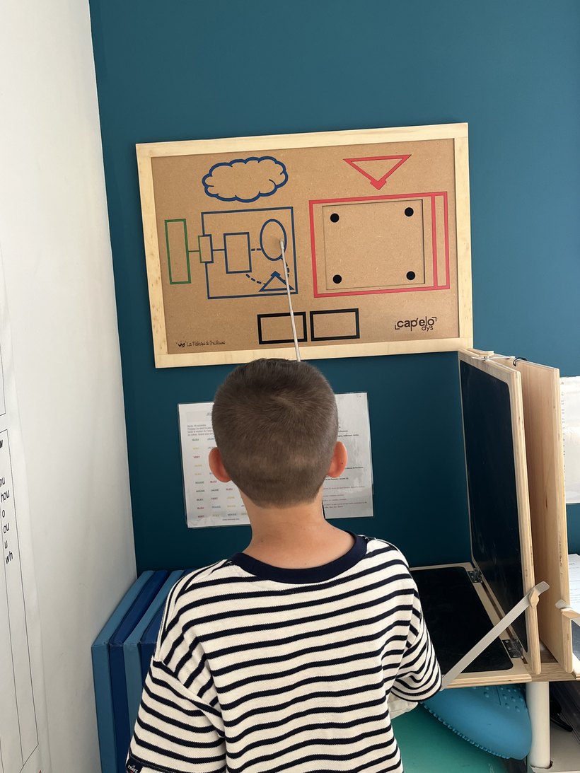 Un élève travaille devant le tableau de grammaire, pendant une séance au cabinet